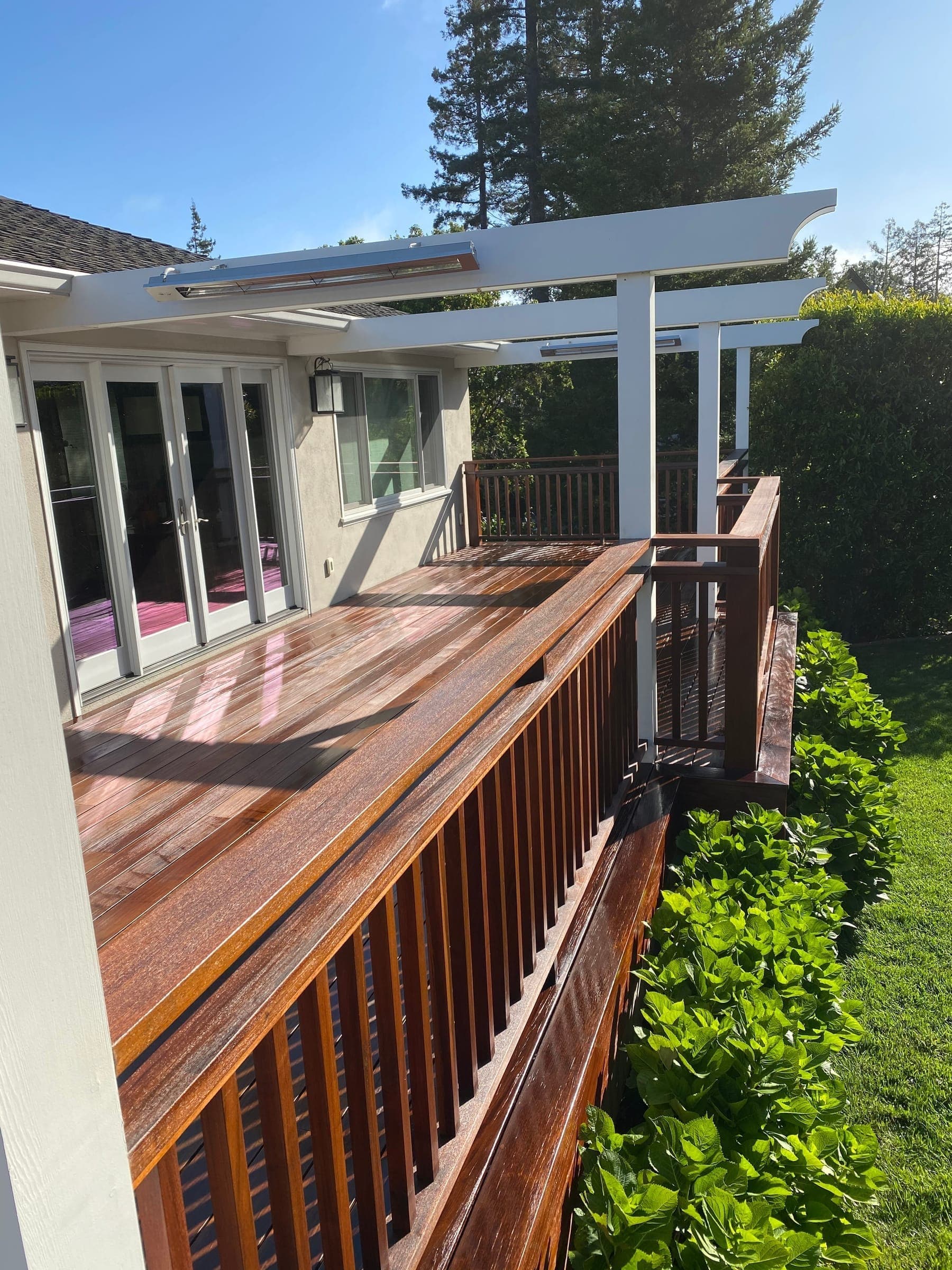 Freshly oiled ipe deck with custom wood railing, French doors, and overhead infrared heaters